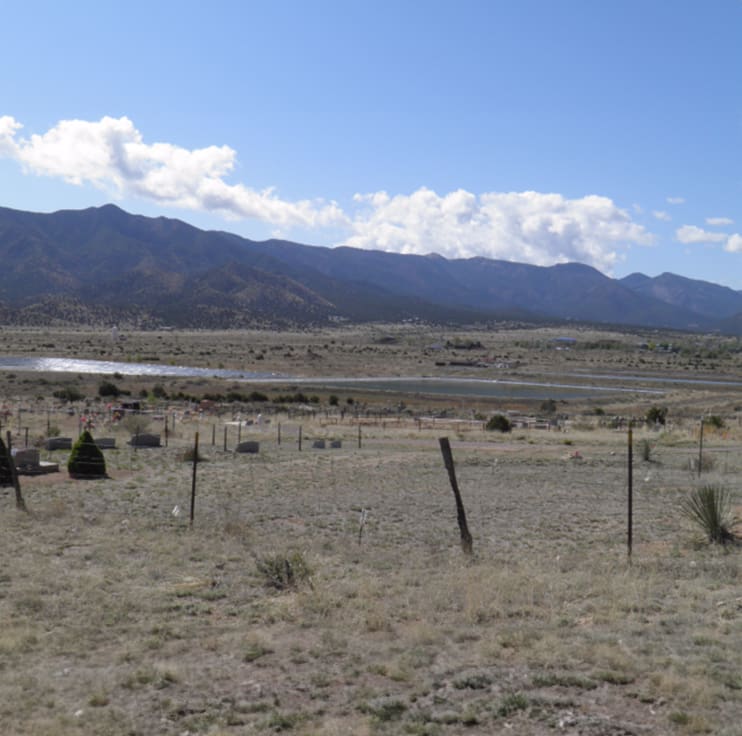 A field with mountains in the background and a lake.