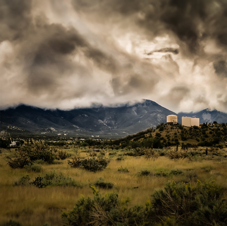 A cloudy sky over a field with some buildings