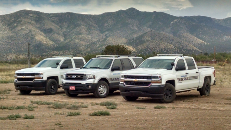 A group of trucks parked in the dirt.