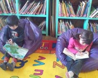 Two children are reading books in a library.